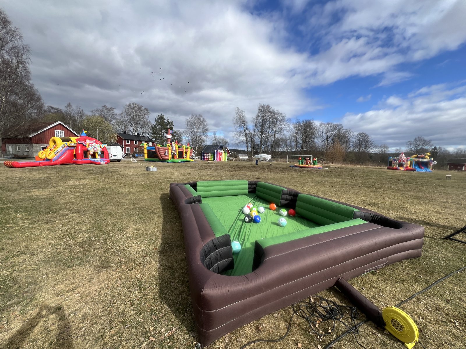 Oppblåsbar biljardfotball på en gressplen, med flere hoppeslott i bakgrunnen