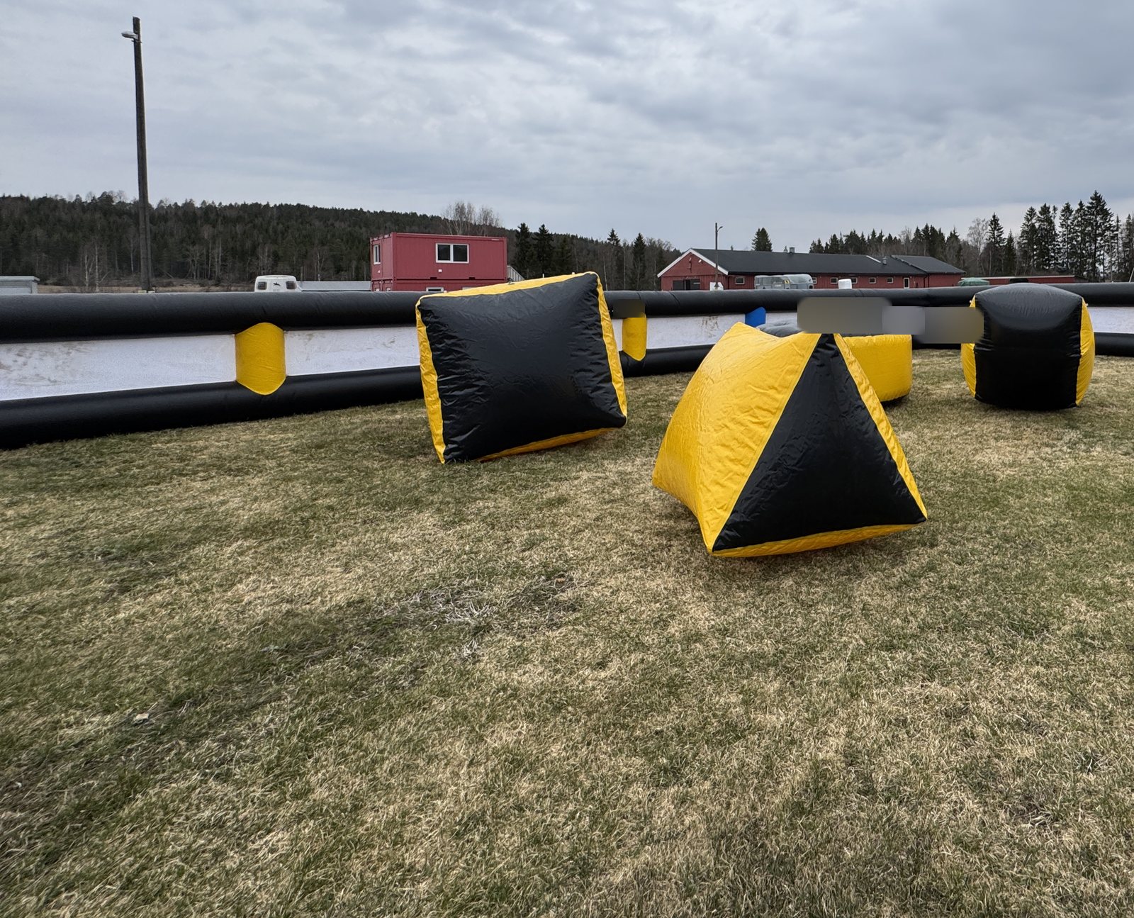 Oppblåsbar arena med gule og svarte hinder på gress