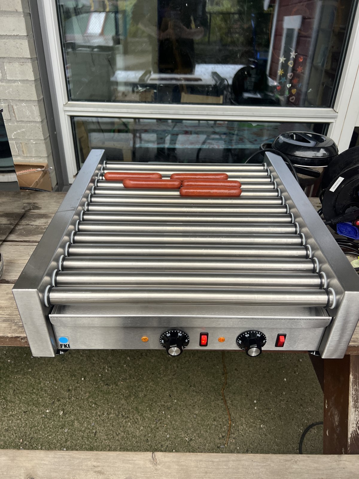 Pølser på en elektrisk pølsegrill med ruller