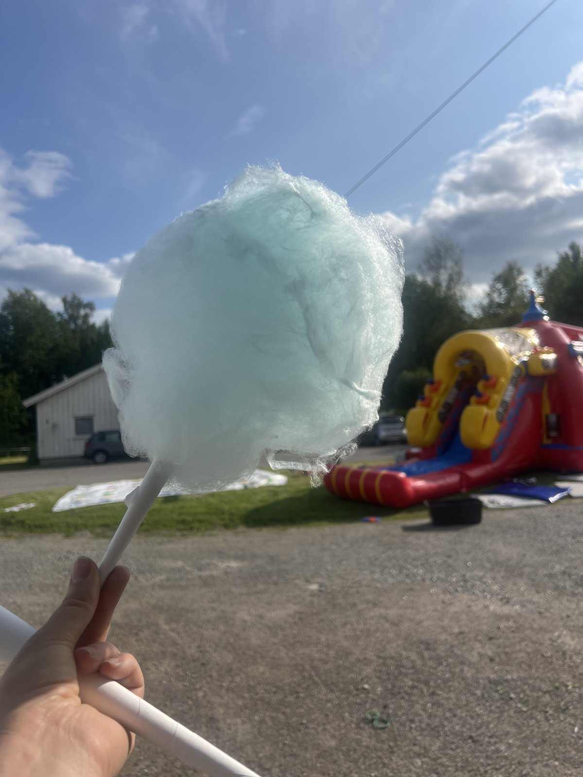 Blå sukkerspinn holdes opp foran et hoppeslott