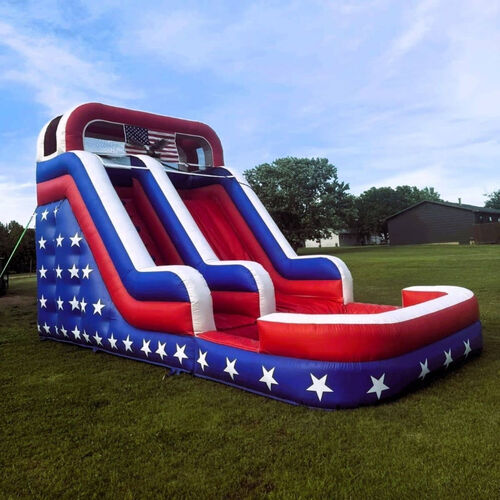Colorful inflatable bounce slide on a grassy yard beside a brick house under a cloudy sky