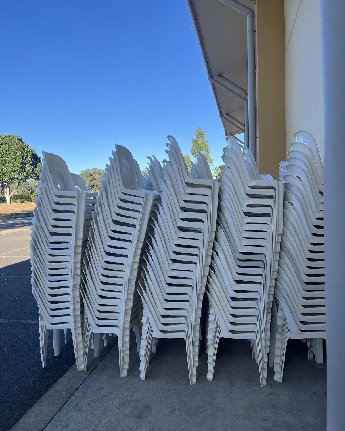 Tall stacks of white plastic chairs lined up and ready for delivery to a Brisbane end-of-year event